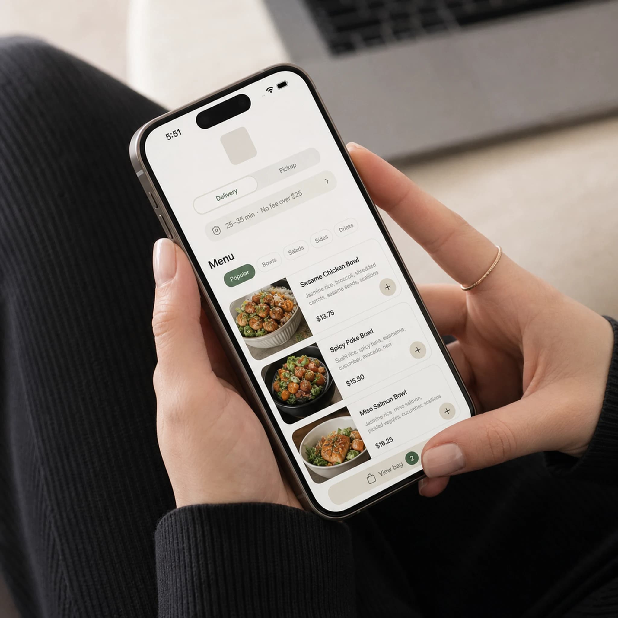 A woman ordering restaurant food at home using her phone and laptop