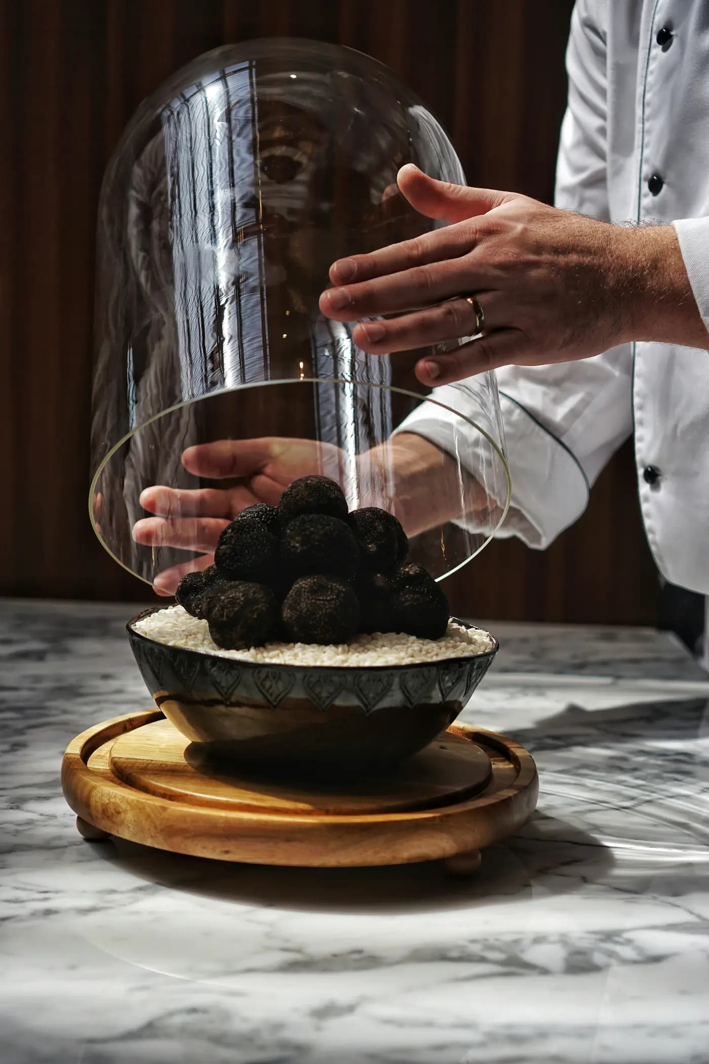 Chef presenting a dish under a glass dome in a restaurant