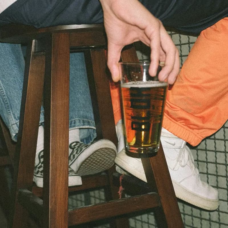 person holding clear drinking glass with brown liquid