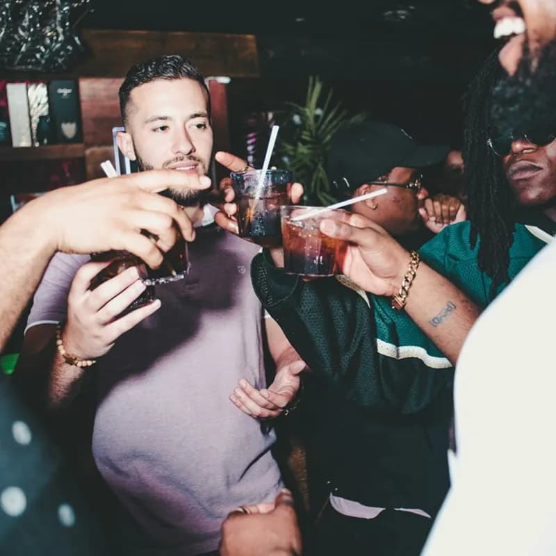 three people holding glass bottles while talking